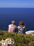 06.09.2017, Spanien, Insel Mallorca, Zwei Urlauber sitzen an der Steilkste am Cap Blanc an den Felsen und schauen auf das blaue weite Mittelmeer.