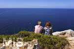 06.09.2017, Spanien, Insel Mallorca, Zwei Urlauber sitzen an der Steilkste am Cap Blanc an den Felsen und schauen auf das blaue weite Mittelmeer.