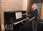 20.02.2018, Kinder und Familie, (Modelreleased). Grundschler spielt Zuhause im Wohnzimmer am Klavier. Die Mutter hilft ihm.