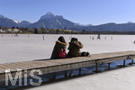 04.03.2018,  Hopfensee in Bayern, Der Hopfensee bei Fssen im Allgu ist ein beliebtes Ausflugsziel auch im Winter.  Der See ist teilweise zugefroren, Schnee liegt auf den Bergen. Zwei Frauen machen Rast auf einem Steg am Ufer bei Hopfen am See.