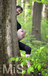 20.04.2019, Schwangere Mutter im 6.Monat. Humor-Foto: Der werdende Vater und die werdende Mutter stehen hinter einem Baum, zu sehen ist der Bauch der Mutter, der Kopf und die Hand des Vaters.  Modelreleased.  
