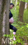 20.04.2019, Schwangere Mutter im 6.Monat. Humor-Foto: Der werdende Vater und die werdende Mutter stehen hinter einem Baum, zu sehen ist der Bauch der Mutter, aber nur der Kopf des Vaters.  Modelreleased.  