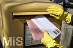 26.03.2020,  Gemeinderatswahl, Brgermeister-Wahl in Bayern 2020, Wahlbezirk Bad Wrishofen in Bayern. Es ist eine Stichwahl ntig, hier whlt eine Brgerin per Briefwahl und wirft den Umschlag mit Schutzhandschuhen in einen Briefkasten, zusammen mit einem Brief fr die Agentur fr Arbeit.