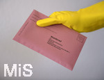 26.03.2020,  Gemeinderatswahl, Brgermeister-Wahl in Bayern 2020, Wahlbezirk Bad Wrishofen in Bayern in Zeiten der Corona-Pandemie. Es ist eine Stichwahl ntig, hier whlt eine Brgerin per Briefwahl und hlt den Umschlag mit Gummihandschuhen in der Hand.