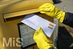 26.03.2020,  Eine Angestellte beantragt aufgrund der Corona-Krise schriftlich Kurzarbeit und wirft mit Gummihandschuhen den Umschlag mit dem Antrag an die Agentur fr Arbeit in einen Briefkasten 