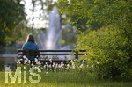 28.05.2020,  Kurpark in Bad Wrishofen, Abendlicht beim Springbrunnen. Eine Frau sitzt einsam auf einer Parkbank, 