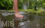 04.08.2020,  Kurpark in Bad Wrishofen im Regenwetter,  Eine Frau luft Barfuss durch eine Pftze am Fischteich. 