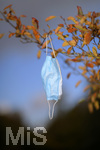 19.10.2020, Symbolbild, Corona-Krise, Eine Einweg-Maske hngt im Baum mit Herbstlaub.