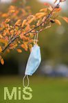 19.10.2020, Symbolbild, Corona-Krise, Eine Einweg-Maske hngt im Baum mit Herbstlaub.