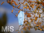 19.10.2020, Symbolbild, Corona-Krise, Eine Einweg-Maske hngt im Baum mit Herbstlaub.