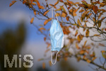 19.10.2020, Symbolbild, Corona-Krise, Eine Einweg-Maske hngt im Baum mit Herbstlaub.