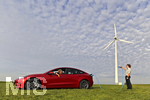 16.08.2021, Symbolbild kostrom fr E-Autos. Ein roter Tesla ldt symbolisch direkt an der Windkraftanlage im Allgu. (Model Release vorhanden) 