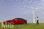 16.08.2021, Symbolbild Ökostrom für E-Autos. Ein roter Tesla lädt symbolisch direkt an der Windkraftanlage im Allgäu. (Model Release vorhanden) 