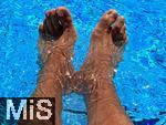 26.07.2022, Schwimmen im Freibad Bad Wörishofen (Bayern),  ein Mann sitzt am Schwimmbecken und lässt seine Beine ins Wasser baumeln.  (Model Release vorhanden)  