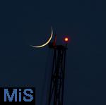 21.05.2023,  Der zunehmende Mond steht als Sichel am Himmel, direkt hinter einer hohen Stütze vom Fahrgeschäft ãSKY SHOTÒ mit dem roten Warnlicht für Flugzeuge im Skylinepark Rammingen.  Fotografiert mit 800mm Teleobjektiv in der Abenddämmerung.