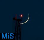 21.05.2023,  Der zunehmende Mond steht als Sichel am Himmel, direkt hinter einer hohen Stütze vom Fahrgeschäft ãSKY SHOTÒ mit dem roten Warnlicht für Flugzeuge im Skylinepark Rammingen.  Fotografiert mit 800mm Teleobjektiv in der Abenddämmerung.