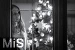 15.11.2023, Weihnachten 2023 in Deutschland, Ein festlich dekorierter Weihnachtsbaum in einer Wohnung im Unterallgäu.  Eine Frau schaut nachdenklich aus dem Wohnzimmer durchs Fenster, sie ist alleine. Thema: Angst vor Einsamkeit am Heiligen Abend. (Modelreleased)