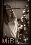 15.11.2023, Weihnachten 2023 in Deutschland, Ein festlich dekorierter Weihnachtsbaum in einer Wohnung im Unterallgäu.  Eine Frau schaut nachdenklich aus dem Wohnzimmer durchs Fenster, sie ist alleine. Thema: Angst vor Einsamkeit am Heiligen Abend. (Modelreleased)