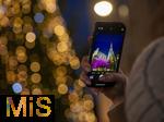20.11.2023, Hauptstadt Wien (Österreich) erstrahlt im vorweihnachtlichem Glanz, Impressionen vom Weihnachtsmarkt am bunt beleuchteten Stephansdom. Eine Touristin fotografiert mit ihrem Handy.