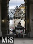 21.11.2023, Österreich, die Hauptstadt Wien. Ein Fiaker fährt Touristen durch die malerische Altstadt durch ein Tor.