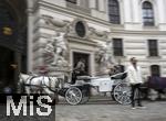 21.11.2023, Österreich, die Hauptstadt Wien. Ein Fiaker fährt Touristen durch die malerische Altstadt durch ein Tor.  