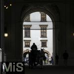 21.11.2023, Österreich, die Hauptstadt Wien. Ein Fiaker fährt Touristen durch die malerische Altstadt durch ein Tor.  
