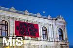 21.11.2023, sterreich, die Hauptstadt Wien. Impressionen vom festlich beleuchteten Burgtheater im Abendlicht. Mit einem Plakat AUFWACHEN BEVOR ES WIEDER FINSTER WIRD, hinten geht der Mond auf.