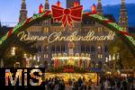 21.11.2023, sterreich, die Hauptstadt Wien. Impressionen vom Weihnachtsmarkt vor dem festlich beleuchteten Rathaus im Abendlicht. Hier das groe Eingangstor mit einem Karussell.