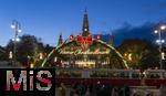 21.11.2023, sterreich, die Hauptstadt Wien. Impressionen vom Weihnachtsmarkt vor dem festlich beleuchteten Rathaus im Abendlicht. Hier das groe Eingangstor, davor fahren Trambahnen vorbei.