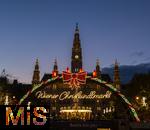 21.11.2023, sterreich, die Hauptstadt Wien. Impressionen vom Weihnachtsmarkt vor dem festlich beleuchteten Rathaus im Abendlicht. Hier das groe Eingangstor mit einem Karussell. 