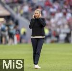 12.05.2024, Fussball 1. Bundesliga 2023/2024, 33.Spieltag, FC Bayern Mnchen - VfL Wolfsburg, in der Allianz-Arena Mnchen.  Kathleen Krger (Teammanagerin) auf dem Feld telefonierend 

