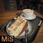 16.01.2025, Bernau am Chiemsee (Bayern), Kaffee und Kuchenpause an einer Raststtte der Autobahn 8. Eine Tiramisu-Torte und ein Cappuccino stehen auf einem Tablett zum Essen bereit.