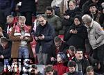 23.02.2025, Fussball 1. Bundesliga 2024/2025, 23. Spieltag,  FC Bayern Mnchen - Eintracht Frankfurt, in der Allianz-Arena Mnchen. Die Zuschauer und Fans schauen immer aufs Handy, Die Hochrechnungen der Bundestagswahl sind raus

