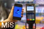 05.05.2025, Symbolbild kontaktloses Bezahlen mit dem iPhone und PaypAl bald auch mglich in Deutschland, eine Frau bezahlt mit Smartphone mittels PayPal-App in einem Laden an der Kasse. 