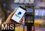 05.05.2025, Symbolbild kontaktloses Bezahlen mit dem iPhone und PaypAl bald auch mglich in Deutschland, eine Frau bezahlt mit Smartphone mittels PayPal-App in einem Laden an der Kasse. 
