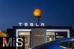 04.05.2025, Bayreuth, (Bayern), Die US-Firma Tesla hat hier einen Ladepark fr E-Autos an der Autobahn A9. An 20 modernen Schnell-Ladesulen knnen hier Teslafahrer und andere E-Auto-Fabrikate ihren Auto-Akku aufladen. Alle Stalls sind Supercharger Version V4. Die Wartezeit knnen sich die Autofahrer in einer Lounge der Firma bk-World vertreiben, mit Toiletten, Ruherume, Getrnke und Snack-Automaten und Sitzmglichkeiten etc.     Hinten ist eine Shell-Tankstelle.