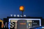 04.05.2025, Bayreuth, (Bayern), Die US-Firma Tesla hat hier einen Ladepark fr E-Autos an der Autobahn A9. An 20 modernen Schnell-Ladesulen knnen hier Teslafahrer und andere E-Auto-Fabrikate ihren Auto-Akku aufladen. Alle Stalls sind Supercharger Version V4. Die Wartezeit knnen sich die Autofahrer in einer Lounge der Firma bk-World vertreiben, mit Toiletten, Ruherume, Getrnke und Snack-Automaten und Sitzmglichkeiten etc.     Hinten ist eine Shell-Tankstelle.