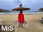 13.06.2024, Beliebtes Reiseziel der Deutschen, die Balearen-Insel Mallorca (Spanien).  Regenwetter am Strand Cala Agulla bei Cala Ratjada,  Badegast sucht Schutz vor dem Regen unter einem Sonnenschirm.
