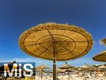 23.06.2025,  Beliebtes Reiseziel der Deutschen, Mallorca.  hier Cala Ratjada am Strand Cala Agulla. Traditionelle Stroh-Sonnenschirme unter blauem Himmel.
