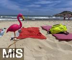 23.07.2025,  Beliebtes Reiseziel der Deutschen, Mallorca. Hier Cala Ratjada am Strand Cala Agulla. Eine pinke Flamingofigur steckt im Sand. Eine Urlaubergruppe aus Deutschland hat diese Spassfigur zum Scherz als Malle-Maskottchen mitgebracht. 