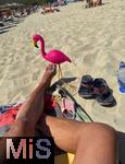 23.07.2025,  Beliebtes Reiseziel der Deutschen, Mallorca. Hier Cala Ratjada am Strand Cala Agulla. Eine pinke Flamingofigur steckt im Sand. Eine Urlaubergruppe aus Deutschland hat diese Spassfigur zum Scherz als Malle-Maskottchen mitgebracht. 