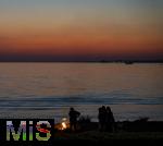 09.08.2025, Bregenz am Bodensee, Abendrot taucht den stillen See in mystisches Licht. Am Ufer hat jemand ein Lagerfeuer entzndet.