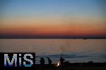09.08.2025, Bregenz am Bodensee, Abendrot taucht den stillen See in mystisches Licht. Am Ufer hat jemand ein Lagerfeuer entzndet.