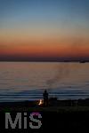 09.08.2025, Bregenz am Bodensee, Abendrot taucht den stillen See in mystisches Licht. Am Ufer hat jemand ein Lagerfeuer entzndet.