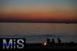 09.08.2025, Bregenz am Bodensee, Abendrot taucht den stillen See in mystisches Licht. Am Ufer hat jemand ein Lagerfeuer entzndet.