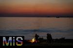 09.08.2025, Bregenz am Bodensee, Abendrot taucht den stillen See in mystisches Licht. Am Ufer hat jemand ein Lagerfeuer entzndet.