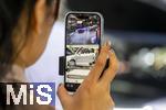 10.09.2025, Messe Mnchen IAA Mobility 2025 in Mnchen im Messegelnde Riem. Mitarbeiterin beim Live-Streaming per Handy am Stand von AITO. AITO ist eine Automarke aus der Volksrepublik China.  AITO ist die erste Marke im Rahmen von Huaweis Harmony Intelligent Mobility Alliance (HIMA). Huawei ist verantwortlich fr Produktdesign, Entwicklung und die Lieferung wichtiger Technologien wie Antriebssysteme, Fahrerassistenzsysteme und Software. 