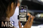 10.09.2025, Messe Mnchen IAA Mobility 2025 in Mnchen im Messegelnde Riem. Mitarbeiterin beim Live-Streaming per Handy am Stand von AITO. AITO ist eine Automarke aus der Volksrepublik China.  AITO ist die erste Marke im Rahmen von Huaweis Harmony Intelligent Mobility Alliance (HIMA). Huawei ist verantwortlich fr Produktdesign, Entwicklung und die Lieferung wichtiger Technologien wie Antriebssysteme, Fahrerassistenzsysteme und Software. 