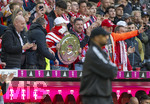 19.04.2026, Fussball Bundesliga 2025/2026, 30.Spieltag, FC Bayern München - VfB Stuttgart, in der Allianz-Arena München, Ein Fan auf der Tribüne hinter der Trainerbank hat eine perfekte Kopie der Meisterschale mitgebracht, Trainer Vincent Kompany (FC Bayern München) beachtet ihn nicht.