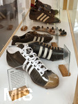 28.05.2026, Fussball DFB-Nationalmannschaft Deutschland. Im Hotel der Medienvertreter, dem Hotel HerzogsPark in Herzogenaurach, kann man gleich am Eingang in den Schaukästen etwas von der Historie des Hotels erfahren. Eng mit dem Namen Adi Dassler ist die Geschichte des Hotels HerzogsPark verbunden. Dort, wo noch
heute die Mannschaften der 1. Fußball Bundesliga logieren, gingen schon Ende der 60er Jahre weltberühmte Sportler ein und aus. Nach den Olympischen Spielen in München wurde aus dem eigens erbauten Gästehaus das Sporthotel adidas. 1992 kaufte
die Tochter Brigitte Baenkler-Dassler das Haus von der adidas AG und baute es zum Hotel HerzogsPark aus. Noch heute wird die Philosophie von Adi Dassler gelebt.  Im Schaukasten historische Adidas-Fussballschuhe aus den Jahren 1954 von der WM in der Schweiz und 1958. 